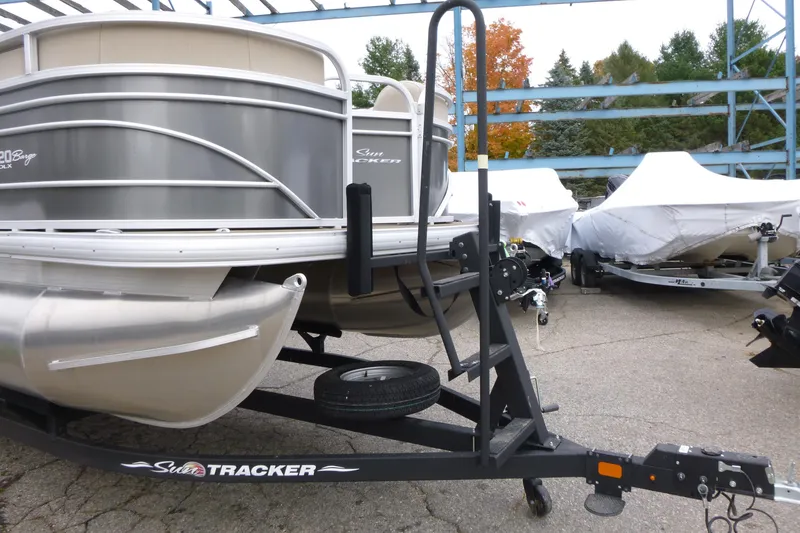 Slide: The Image of 2023 Sun Tracker Party Barge 20 DLX pontoon boat on trailer in storage area. - 2