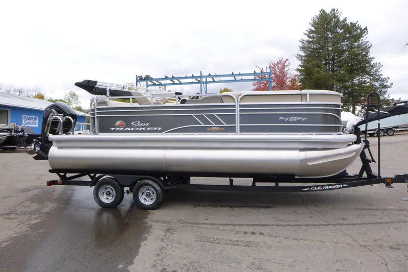 Slide: The Image of 2023 Sun Tracker Party Barge 20 DLX pontoon boat on trailer, parked outdoors. - 20