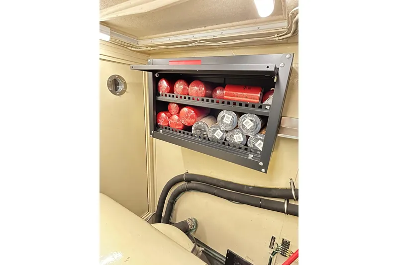 Slide: The Image of Storage compartment with red and silver items inside a 1979 Hatteras 53 Motor Yacht Hard Top. - 102
