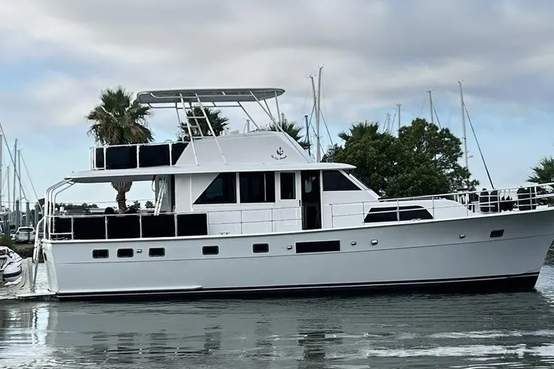 Slide: The Image of 1979 Hatteras 53 Motor Yacht Hard Top on calm water, docked near palm trees. - 12