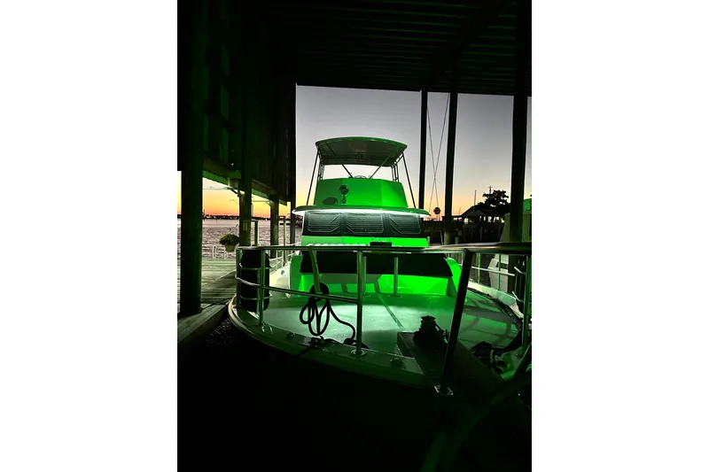 Slide: The Image of 1973 Hatteras 53 Motor Yacht with green lighting at sunset in a marina. - 144