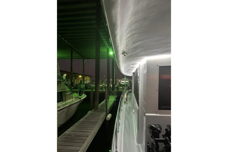 Slide: The Image of 1973 Hatteras 53 Motor Yacht Hard Top docked under green-lit shelter. - 156
