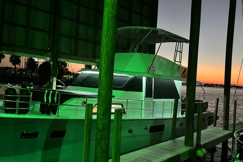 Slide: The Image of 1973 Hatteras 53 Motor Yacht Hard Top docked at sunset, illuminated in green light. - 157