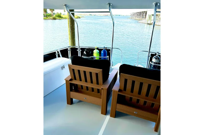 Slide: The Image of 1979 Hatteras 53 Motor Yacht Hard Top with wooden chairs overlooking serene water. - 35