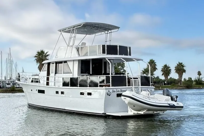 Slide: The Image of 1979 Hatteras 53 Motor Yacht Hard Top on calm water, with palm trees in background. - 8