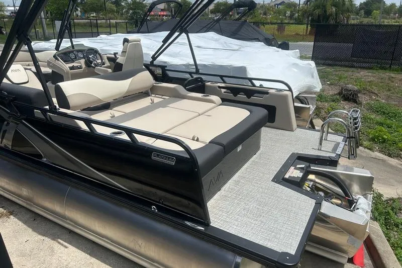 Slide: The Image of 2025 Avalon LSZ Versatile pontoon boat with rear bench seating, docked outdoors. - 6