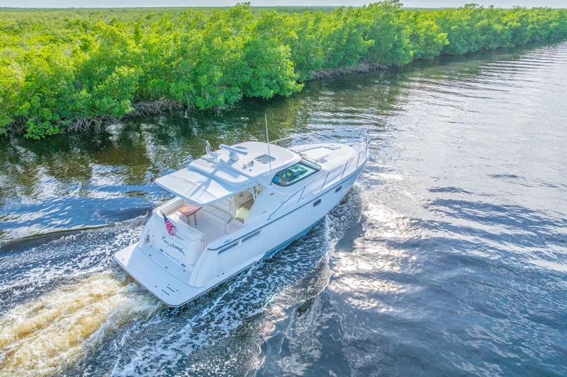 Slide: The Image of 2011 Tiara Yachts 4300 Sovran cruising on a scenic waterway with lush greenery. - 5