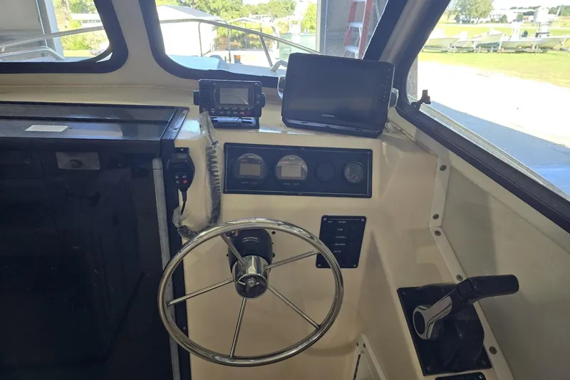 Slide: The Image of Interior view of a 2000 Maycraft Pilot House 2300 boat cockpit with steering wheel and navigation equipment. - 4