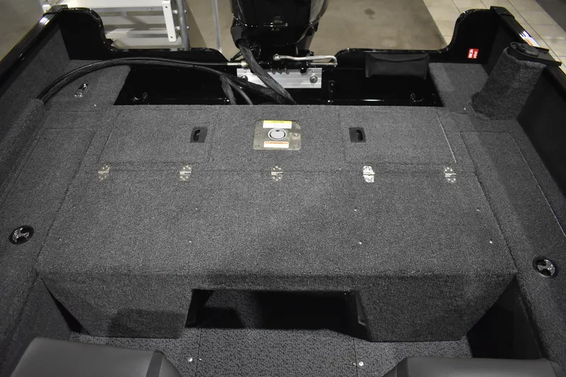 Slide: The Image of 2026 Lund 1650 Rebel XL Sport boat interior with storage compartments and carpeted flooring. - 17