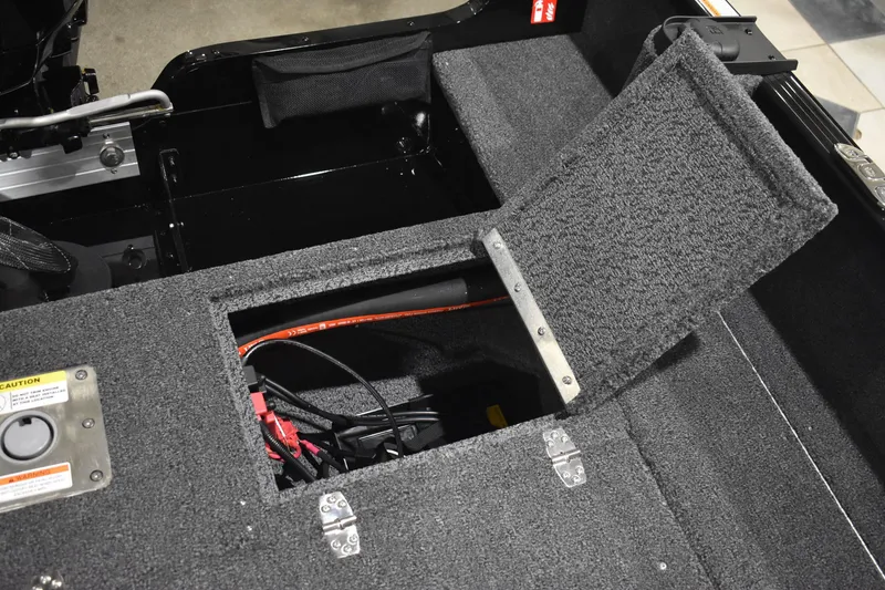 Slide: The Image of Open storage compartment in 2026 Lund 1650 Rebel XL Sport boat, showing wiring and carpeted interior. - 19