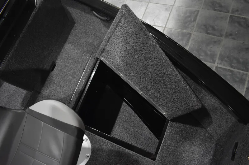 Slide: The Image of 2026 Lund 1650 Rebel XL Sport boat interior with open storage compartment and seat. - 21