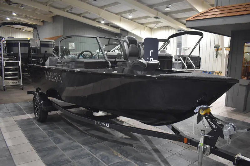 Slide: The Image of 2026 Lund 1650 Rebel XL Sport boat displayed in showroom, sleek black design. - 3