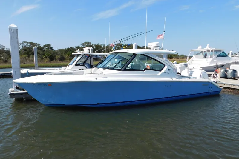The Image of 2024 Pursuit DC 326 Dual Console boat docked in a marina, side view. - 0