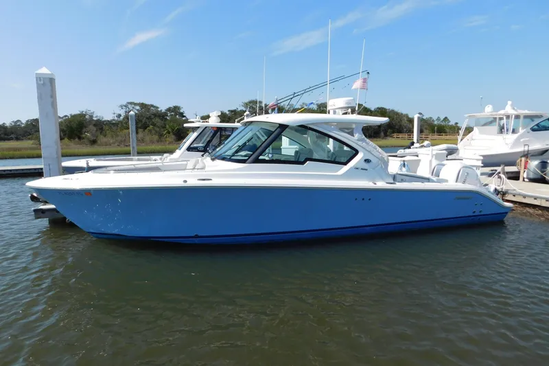 Slide: The Image of 2024 Pursuit DC 326 Dual Console boat docked in a marina. - 2