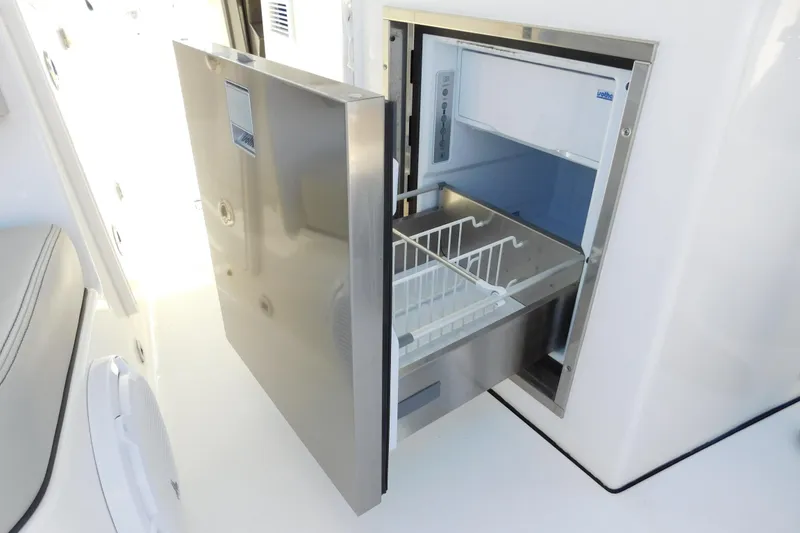 Slide: The Image of 2024 Pursuit DC 326 Dual Console boat with open stainless steel refrigerator. - 25