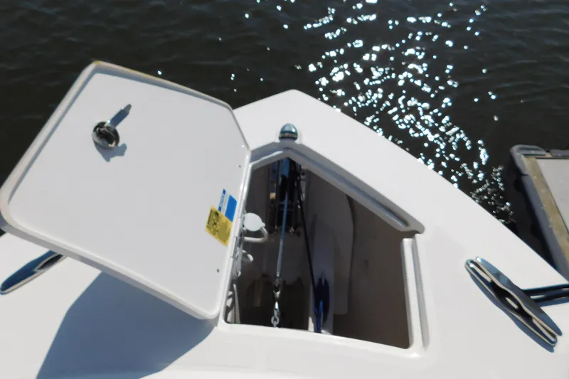 Slide: The Image of 2024 Pursuit DC 326 Dual Console anchor locker open on calm water. - 53