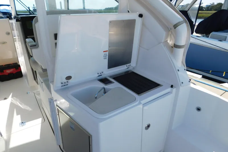 Slide: The Image of 2024 Pursuit DC 326 Dual Console boat interior with sink and storage area. - 69