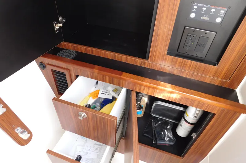 Slide: The Image of 2024 Pursuit DC 326 Dual Console interior storage with wooden cabinets and electrical panel. - 77