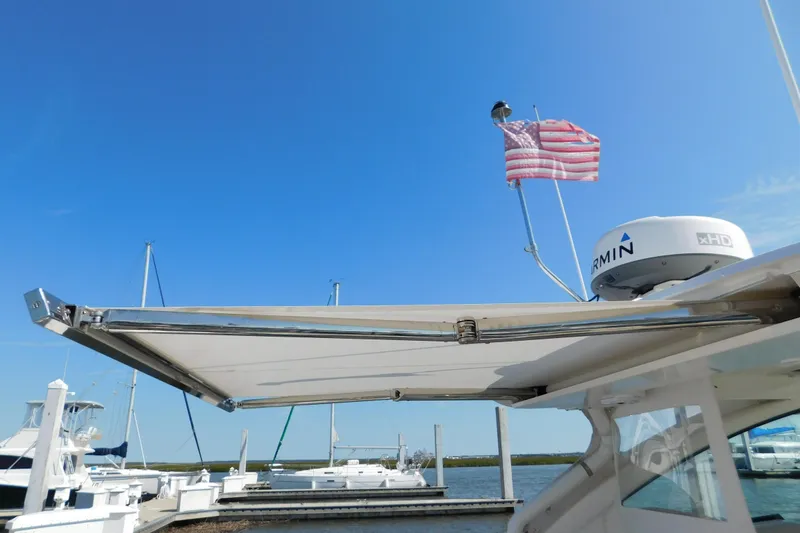 Slide: The Image of 2024 Pursuit DC 326 Dual Console boat with radar and American flag at marina. - 86