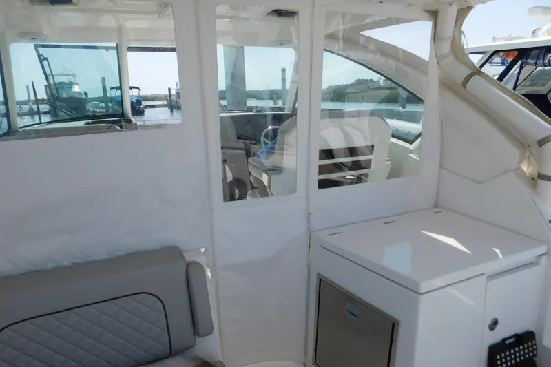 Slide: The Image of 2024 Pursuit DC 326 Dual Console interior with seating and storage, docked at marina. - 94