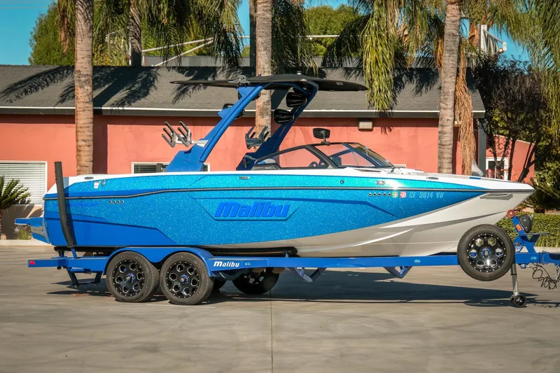 The Image of 2021 Malibu Wakesetter 23 LSV boat in vibrant blue on a trailer, parked outdoors. - 1