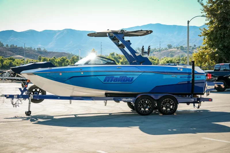 Slide: The Image of 2021 Malibu Wakesetter 23 LSV boat on trailer, parked with scenic mountain backdrop. - 2