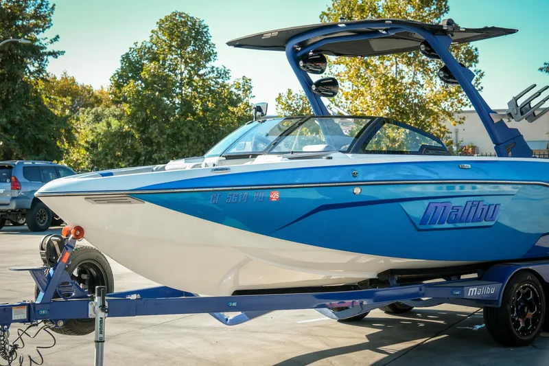 Slide: The Image of 2021 Malibu Wakesetter 23 LSV boat on trailer, blue and white design, parked outdoors. - 3