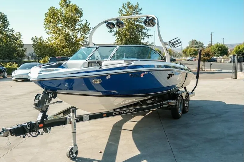 Slide: The Image of 2014 Centurion Enzo SV233 boat on trailer, blue and white, parked outdoors. - 2