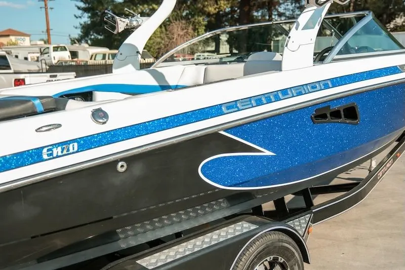 Slide: The Image of 2014 Centurion Enzo SV233 boat with blue and white detailing on a trailer. - 31