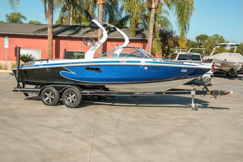 Slide: The Image of 2014 Centurion Enzo SV233 boat on trailer, parked outdoors with palm trees in background. - 6
