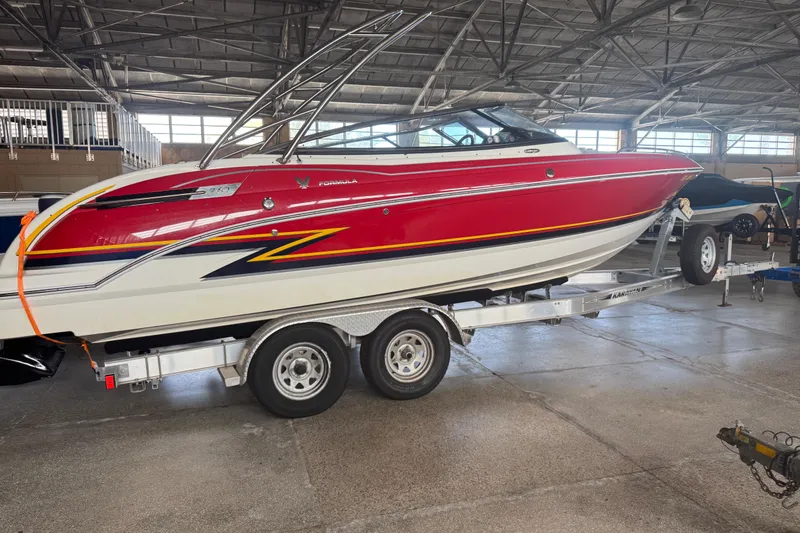The Image of 2017 Formula 240 Bowrider boat on trailer, red and white, parked outside stone building. - 0