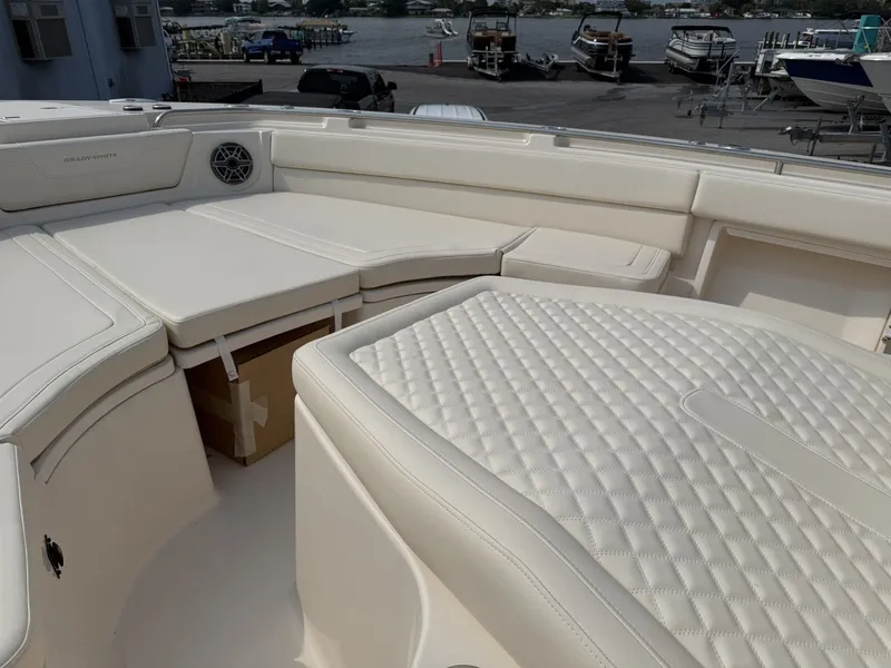 Slide: The Image of The image shows the luxurious, cushioned deck of a Grady-White Canyon 386 boat at the harbor. - 15