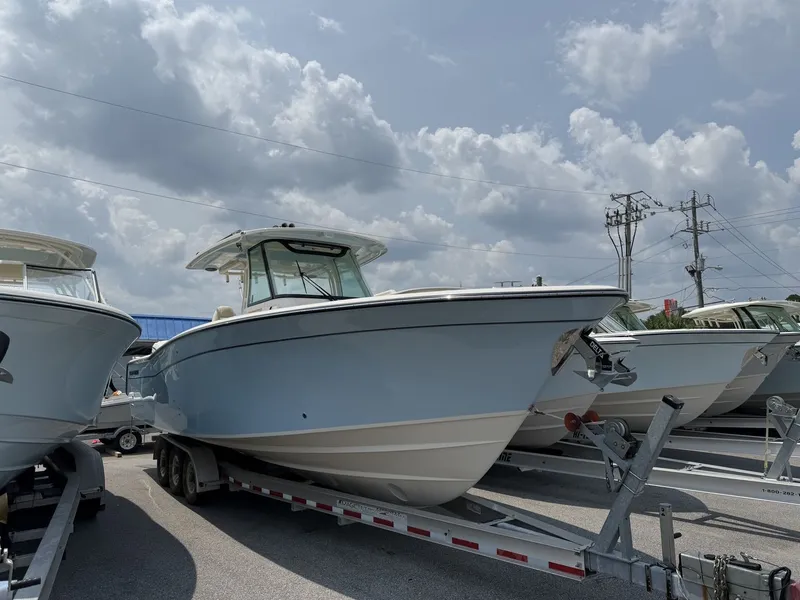 Slide: The Image of 2026 Grady-White Canyon 336 on a trailer, surrounded by other boats, under a cloudy sky. - 0