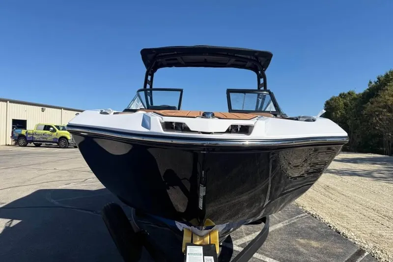 Slide: The Image of 2026 Yamaha Boats 252SD, sleek black hull, parked outdoors under clear blue sky. - 2