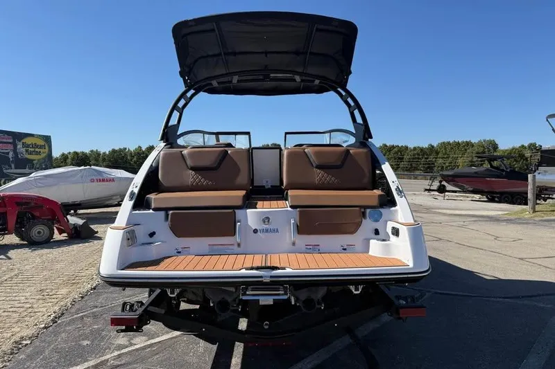 Slide: The Image of 2026 Yamaha Boats 252SD with brown seating and black canopy, parked outdoors. - 5