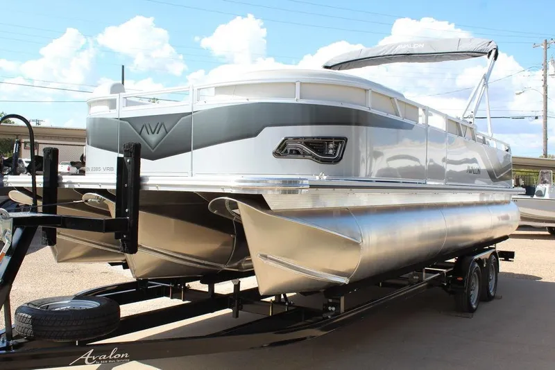 Slide: The Image of 2025 Avalon Venture 85 Versatile Rear Bench 23 FT pontoon boat on trailer, under clear sky. - 9