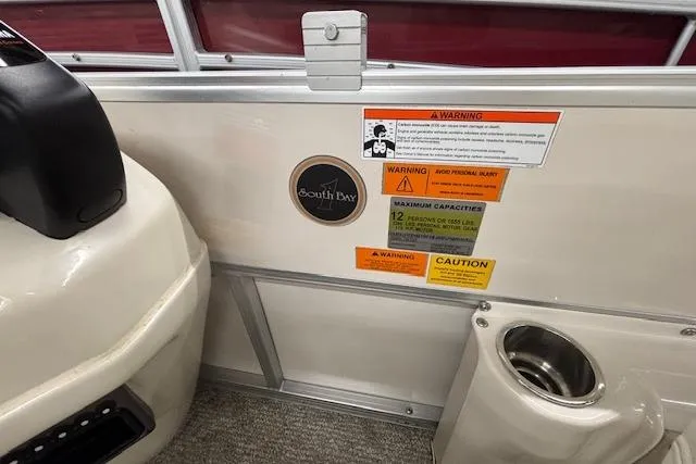 Slide: The Image of Interior of a 2009 South Bay 722 FCR boat with safety warnings and cup holder. - 8