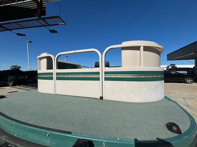 Slide: The Image of 1999 Crestliner 2480 SPORT LX pontoon boat with green and white design, docked under clear blue sky. - 7