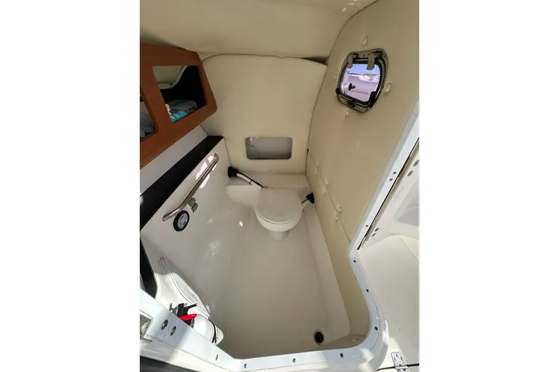 Slide: The Image of Interior of 2014 Edgewater 245CX Crossover boat, featuring a compact marine toilet. - 12