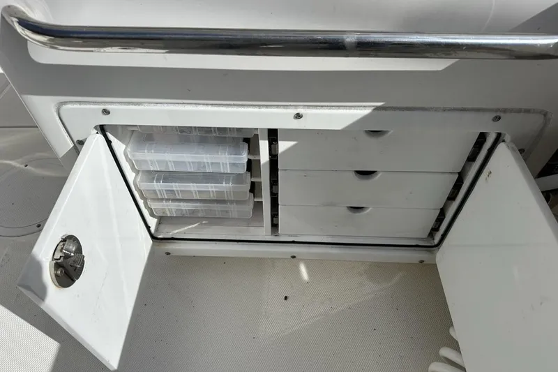 Slide: The Image of Storage compartment on a 2014 Edgewater 245CX Crossover boat with open doors and drawers. - 19