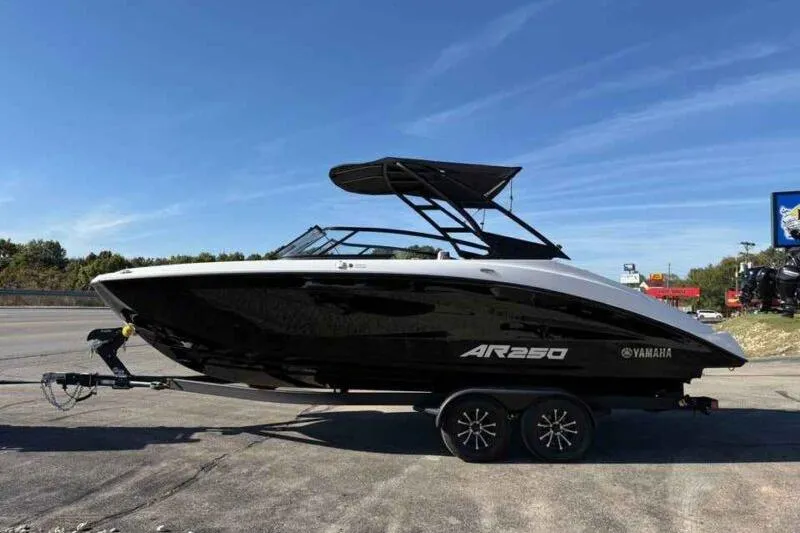 The Image of 2026 Yamaha Boats AR250 on trailer, sleek black and white design, parked outdoors. - 0