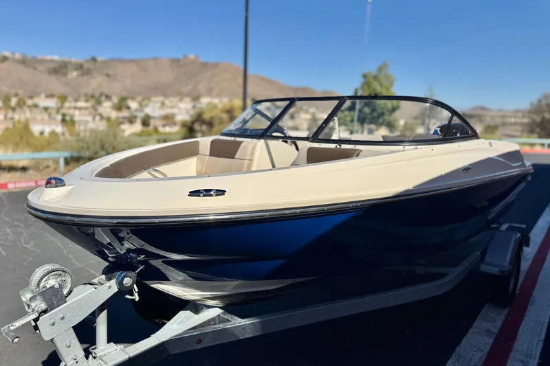 Slide: The Image of 2019 Bayliner 180 Bowrider boat on trailer, parked outdoors with scenic background. - 3