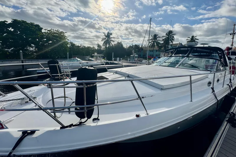 Slide: The Image of 1998 Sea Ray 400 Sundancer yacht docked under a partly cloudy sky. - 2