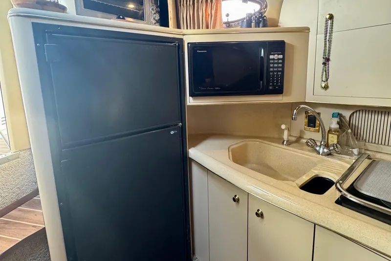 Slide: The Image of Kitchen area of 1998 Sea Ray 400 Sundancer with fridge, microwave, and sink. - 9