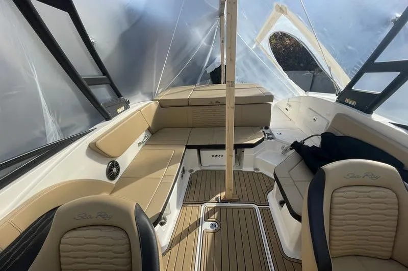 Slide: The Image of 2024 Sea Ray 230 Sportster Bow Rider interior with tan seating and wood accents. - 7