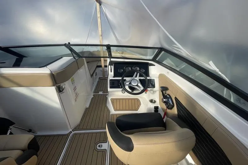 Slide: The Image of 2024 Sea Ray 230 Sportster Bow Rider interior with steering wheel and seating. - 9