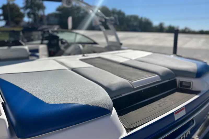 Slide: The Image of 2015 Moomba Mobius LSV boat with blue and white interior, parked outdoors. - 15