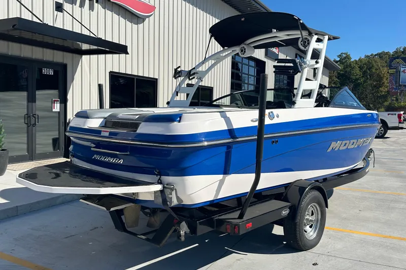 Slide: The Image of 2015 Moomba Mobius LSV boat in blue and white, parked on a trailer. - 5