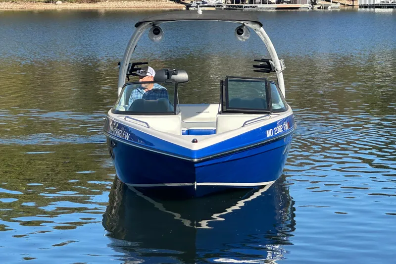 Slide: The Image of 2015 Moomba Mobius LSV boat on a serene lake with lush greenery in the background. - 52