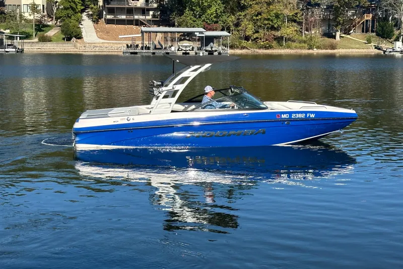 Slide: The Image of 2015 Moomba Mobius LSV boat on a calm lake, with a person at the helm. - 58